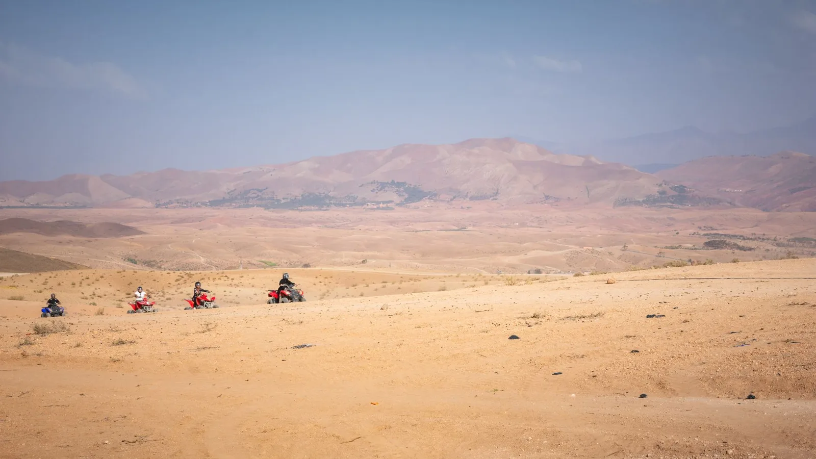 Varios quads recorriendo el desierto de Agafay, con montañas al fondo